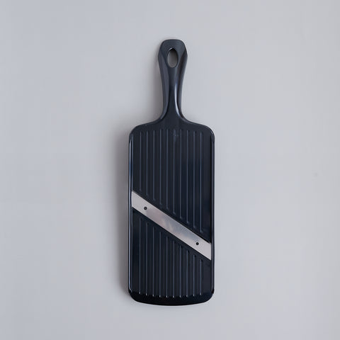 Left-handed vegetable slicer with stainless steel angled blade and safety holder, made in Japan.
