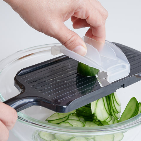 Left-handed vegetable slicer with stainless steel angled blade and safety holder, made in Japan.
