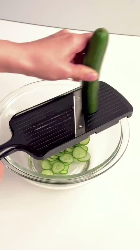Left-handed vegetable slicer with stainless steel angled blade and safety holder, made in Japan.