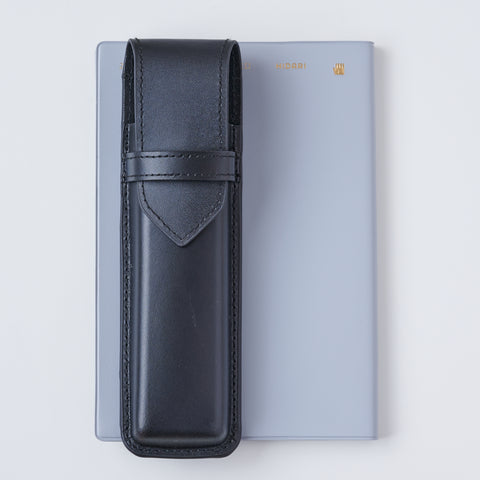 Recycled leather book strap pencil case with adjustable elastic band, shown attached to a notebook.