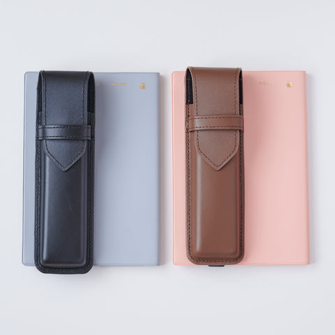 Recycled leather book strap pencil case with adjustable elastic band, shown attached to a notebook.