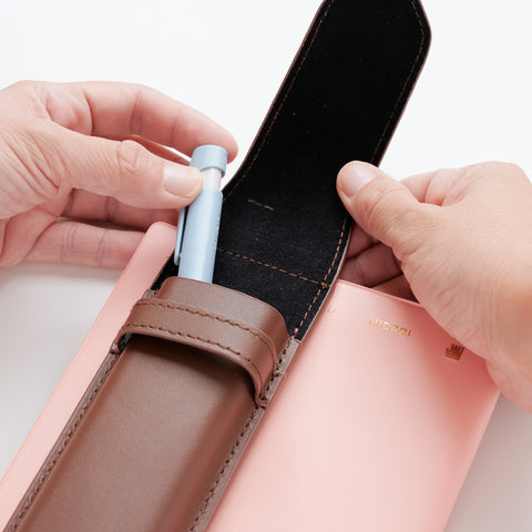Recycled leather book strap pencil case with adjustable elastic band, shown attached to a notebook.