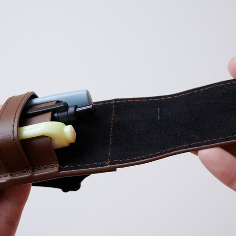 Recycled leather book strap pencil case with adjustable elastic band, shown attached to a notebook.