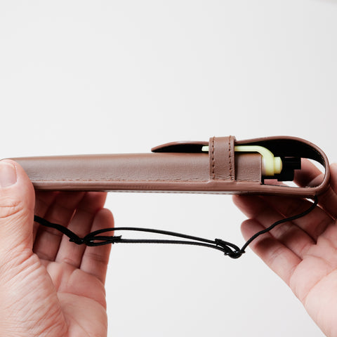 Recycled leather book strap pencil case with adjustable elastic band, shown attached to a notebook.
