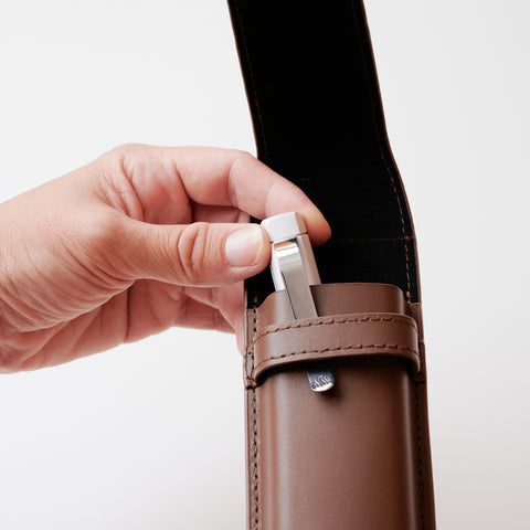 Recycled leather book strap pencil case with adjustable elastic band, shown attached to a notebook.