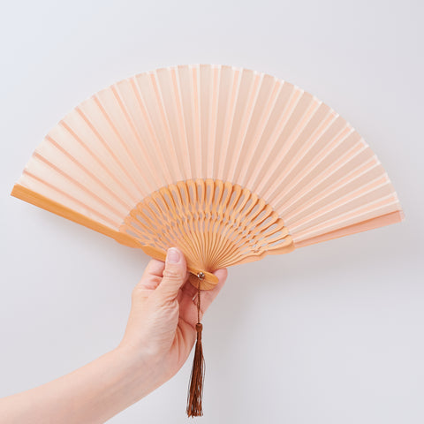 folding fan (with light brown ribs), left-handed